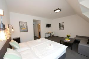 a bedroom with a white bed and a living room at Penzion FORMULA in Trenčín