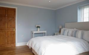 1 dormitorio con cama blanca y puerta de madera en Moss Cottage, en Bickley