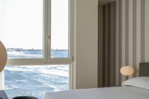 a bedroom with a window looking out at the ocean at Hotel Punta Tipa in Trapani