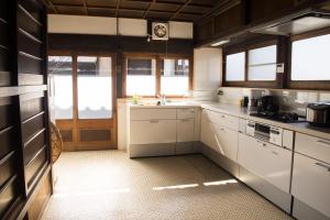 a kitchen with white cabinets and a sink and windows at tehen in Kyoto