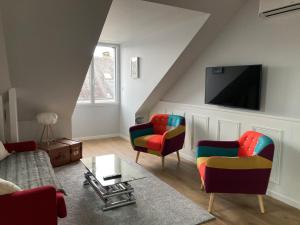sala de estar con sillas coloridas y TV de pantalla plana en 3 Appartements SCI Jape en Blois