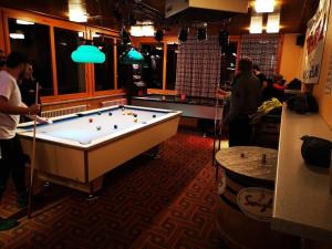 a pool table in a room with people standing around at Adrenalin Backpackers Hostel in Braunwald