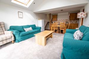 a living room with two blue couches and a kitchen at Long Byres Holiday Cottages in Brampton