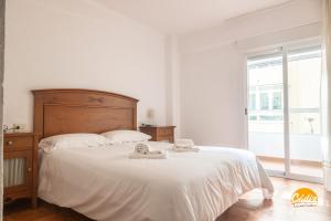 a bedroom with a bed with white sheets and a window at Villa Lola by Cadiz Time in Cádiz