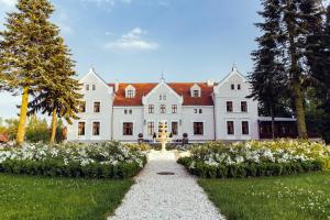duży biały dom z ogrodem przed nim w obiekcie Palac Mortegi Hotel & SPA- Restauracja Szlachecka, SPA, Basen, Sauny, Jazda Konna, Mini Zoo- Luksus, Relaks i Przyroda w jednym! w mieście Lubawa