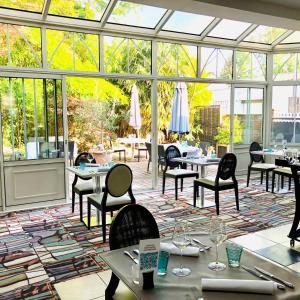 a conservatory with tables and chairs and windows at The Originals Boutique, Hôtel Bulles by Forgeron, Lille Sud (Qualys-Hotel) in Seclin