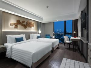 a hotel room with two beds and a desk at Royal Malioboro by ASTON in Yogyakarta