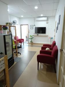 a waiting room with red chairs and a flat screen tv at Aban Transit House in Kuala Besut