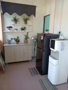 a kitchen with a refrigerator and potted plants on shelves at Aban Transit House in Kuala Besut
