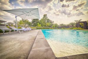 uma piscina com cadeiras e um guarda-sol ao lado de uma piscina em Il Casale di Monacella em Santa Venerina