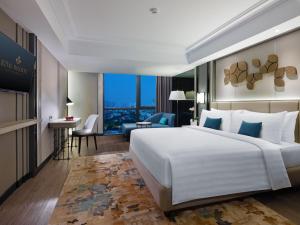 a hotel room with a large bed and a desk at Royal Malioboro by ASTON in Yogyakarta