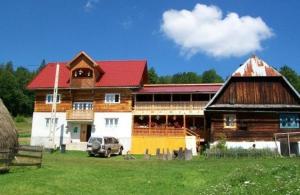 un gran edificio de madera con techo rojo en Pensiunea Scarisoara en Gheţari