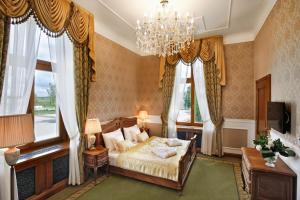 sypialnia z łóżkiem, żyrandolem i oknami w obiekcie Palac Mortegi Hotel & SPA- Restauracja Szlachecka, SPA, Basen, Sauny, Jazda Konna, Mini Zoo- Luksus, Relaks i Przyroda w jednym! w mieście Lubawa