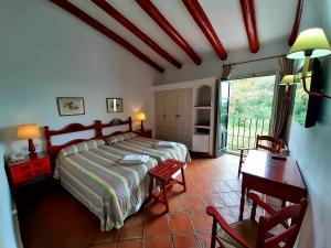 Schlafzimmer mit einem Bett, einem Schreibtisch und einem Tisch in der Unterkunft Finca Valbono Apartamentos Rurales y Hotel in Aracena