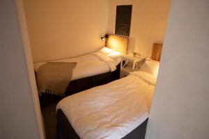 two beds in a small room with white sheets at Peppinge Bed & Breakfast in Löderup