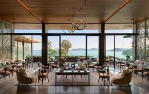 パナワビーチにあるV ヴィラズ プーケット - M ギャラリーのテーブルと椅子と窓のある広い部屋