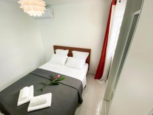 - une chambre avec un lit, des serviettes et une fleur dans l'établissement Le Cocon vous accueille avec plaisir !, à Fort-de-France