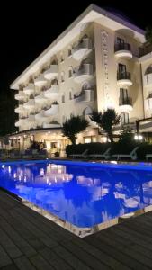 un hôtel avec une piscine en face d'un bâtiment dans l'établissement Hotel Nettuno, à Cervia