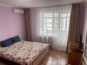 a bedroom with a bed and a large window at Апартаменты на ГОГОЛЯ,460 in Cherkasy