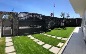 un jardín con una puerta negra y césped verde en Casa Vacanze La Conca, en San Giovanni la Punta