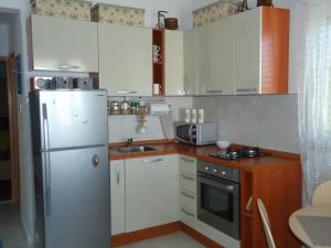 a small kitchen with white cabinets and a refrigerator at Apartment Lucija on the sandy beach in Drvenik Mali