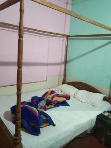 a bed in a room with a canopy bed with a white sheet at Vamoose Nirmala in Kailāshahar