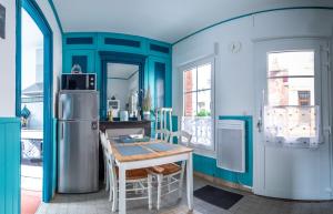 a blue kitchen with a table and a refrigerator at Villa Coppi in Le Tréport