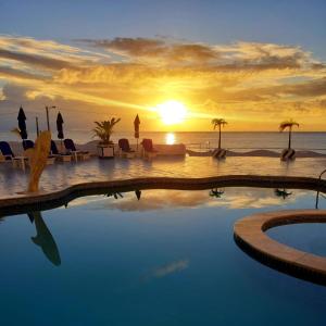 uma piscina com um pôr-do-sol sobre o oceano em New Casablanca Praia Hotel em Paulista