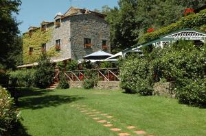 ein Steingebäude mit einem Sonnenschirm in einem Garten in der Unterkunft La Riserva Montebello in Bolsena