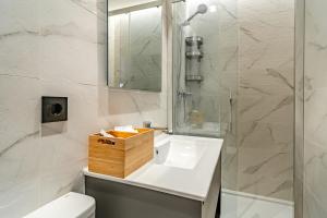 a bathroom with a white sink and a shower at Edificio Fénix by Plaza Mayor Apartamentos in Valladolid +94 photos