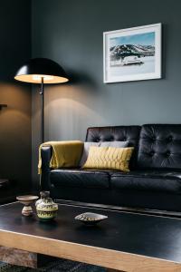 un sofá de cuero negro en una sala de estar con mesa en Solbakki, en Flateyri
