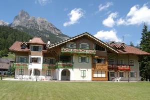 a large house with a mountain in the background at Residence Holiday in Pozza di Fassa