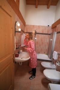 a woman standing in a bathroom with a sink at Residence Holiday in Pozza di Fassa