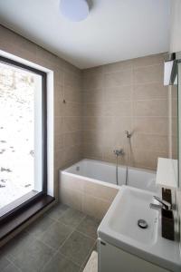 uma casa de banho com uma banheira, um lavatório e uma janela em Apartmán Lúčnica em Bystrá