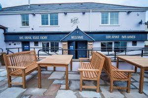 three wooden tables and chairs in front of a building at Brunel Inn in Saltash