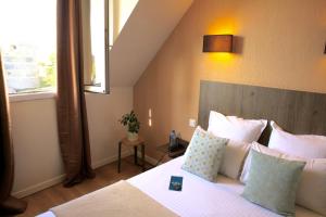 Cama ou camas em um quarto em Logis Hôtels- Hôtel Marguerite d'Anjou Angers château