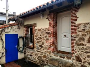 a brick house with a blue door and a window at Casa Rural Alto Santiago in Santiago del Collado