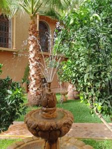 a fountain in the middle of a yard with trees at Les Jardins de Ryad Bahia in Meknès