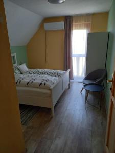 ヴィッラーニにあるBurai Vendégházのベッドルーム1室(ベッド1台、椅子、窓付)