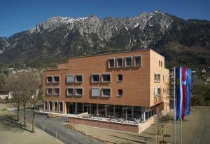 a large brick building with mountains in the background at Schaan-Vaduz Youth Hostel in Schaan