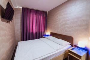 バラシハにあるNovokosino Hotelのベッドルーム1室(ベッド1台付)、紫色のカーテン付きの窓が備わります。