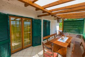 a porch with a wooden table and chairs and green shutters at JELICIC C in Crikvenica