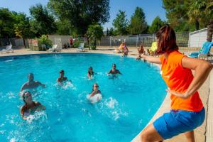 a group of people playing in a swimming pool at Mobile home tout confort Alexandre in La Roque-dʼAnthéron