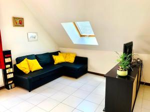 sala de estar con sofá negro y almohadas amarillas en Le Paraty - Maison indépendante 72 m2, en Pont-Sainte-Maxence