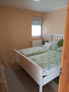 ヴィッラーニにあるDűlő Apartmanházのベッドルーム1室(白いベッド1台、緑の掛け布団付)