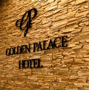 um sinal para um hotel palácio dourado numa parede de tijolos em Golden Palace em Aktau