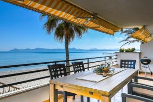 een houten tafel op een balkon met uitzicht op de oceaan bij ☆TRAUMHAFTE LAGE, DIREKTER STRANDZUGANG, 6 GÄSTE☆ in Alcudia