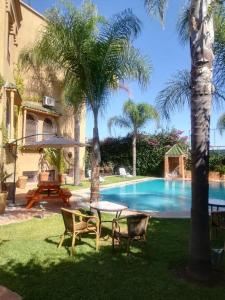 un patio con mesa y sillas junto a una piscina en Les Jardins de Ryad Bahia en Meknès