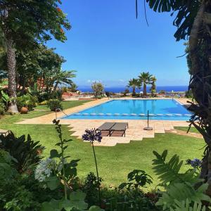 a large swimming pool in a yard with trees and the ocean at Quinta Splendida Wellness & Botanical Garden in Caniço