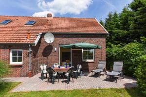 Cette maison en briques dispose d'une terrasse avec une table et des chaises. dans l'établissement Ferienwohnungen im Haus Eversmeer, à Eversmeer